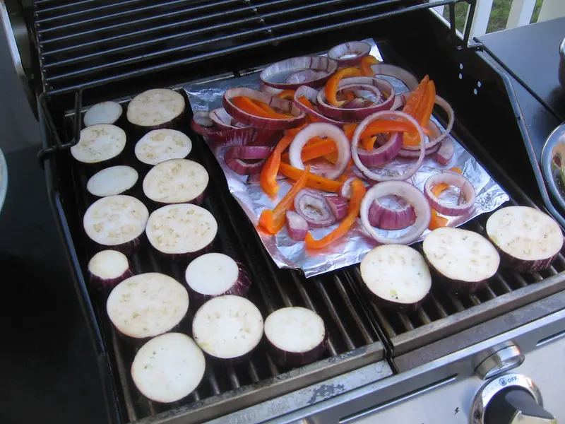 shown is a photo of eggplant and other vegetables on a grill getting grilled