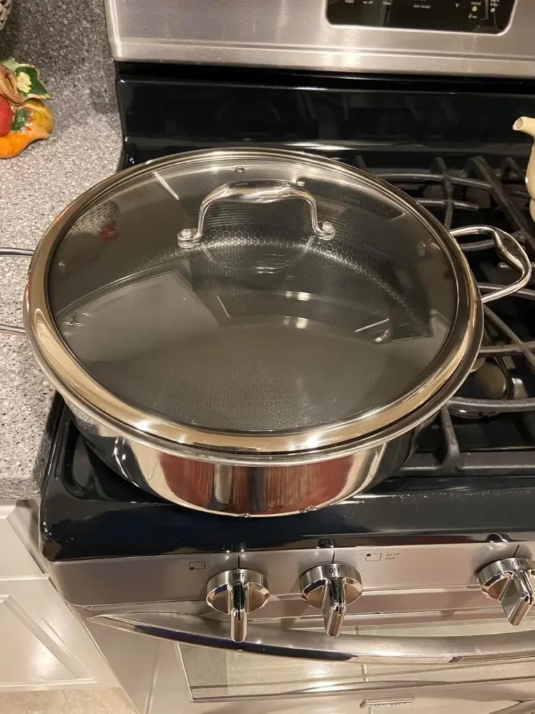 HexClad Hybrid Nonstick Sauté Pan with its lid covered on top of a cooktop for our best nonstick saute pan test